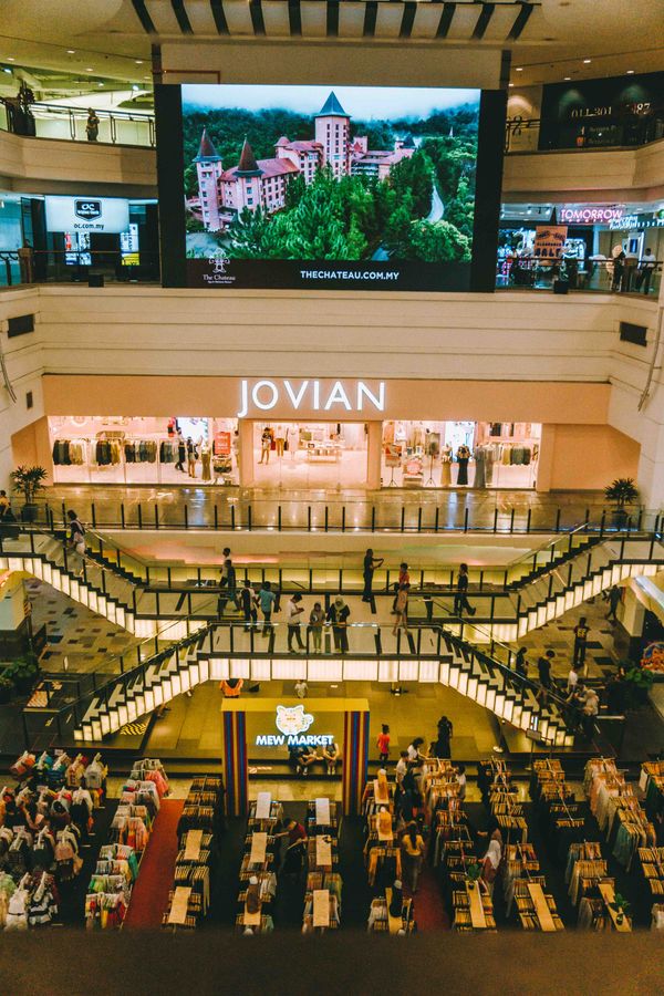 Shoppers watching a large digital ad screen inside a busy store concourse