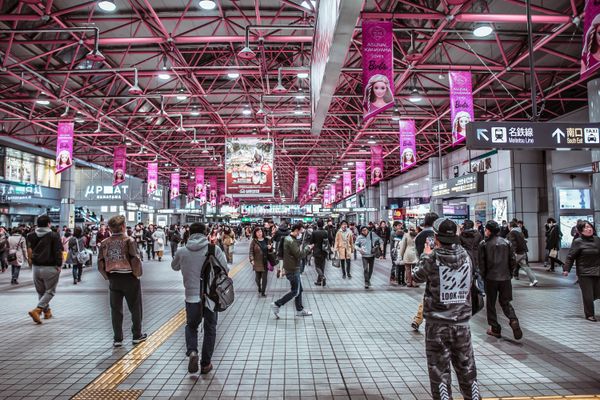 Train station concourse with digital banner screens and crowds
